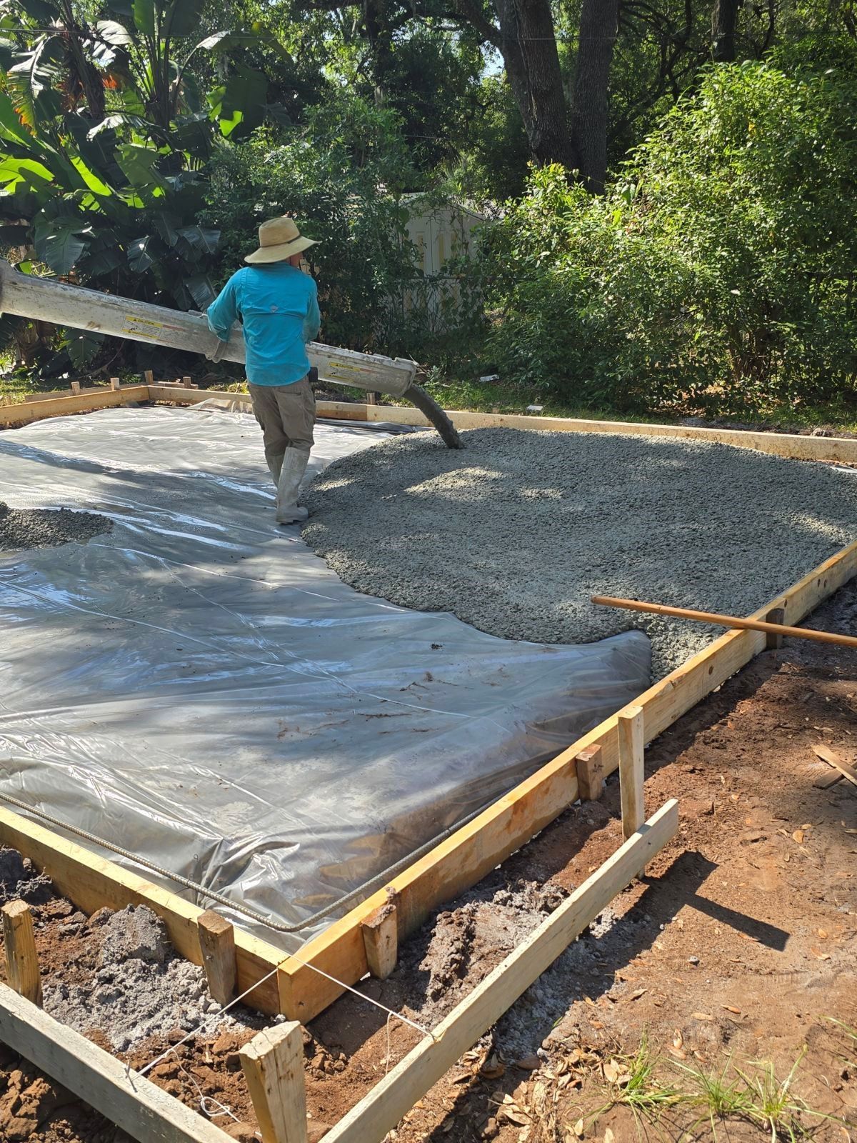 A man is pouring concrete into a foundation.