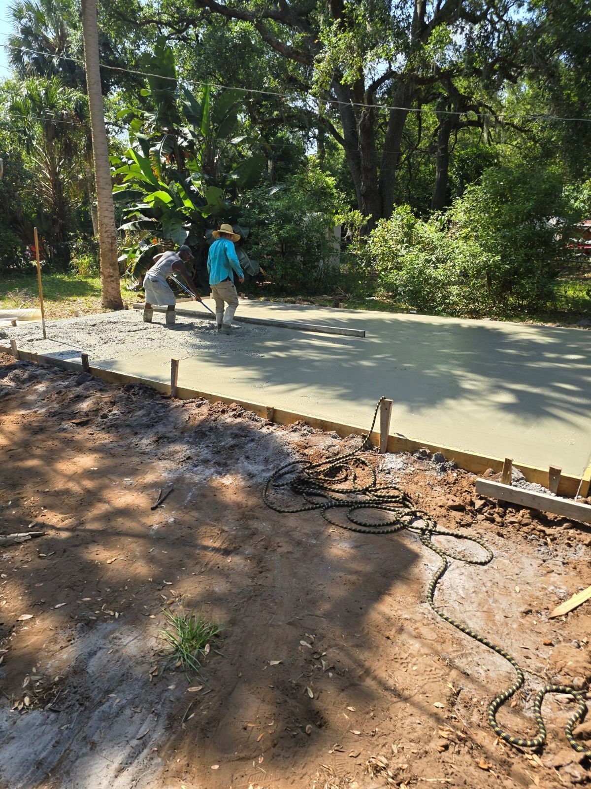 Two men are working on a concrete driveway.