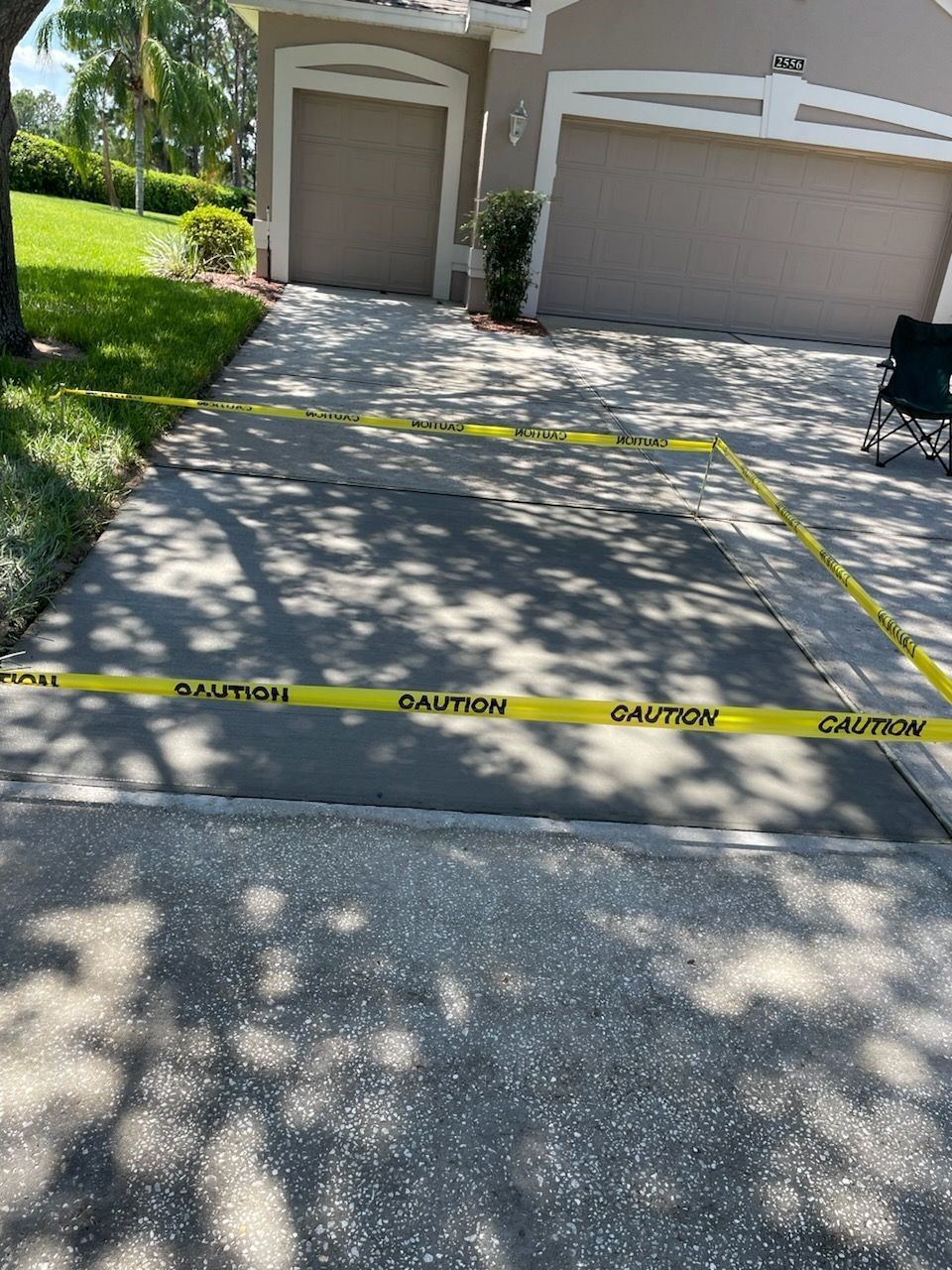 A concrete driveway with a yellow caution tape on it.