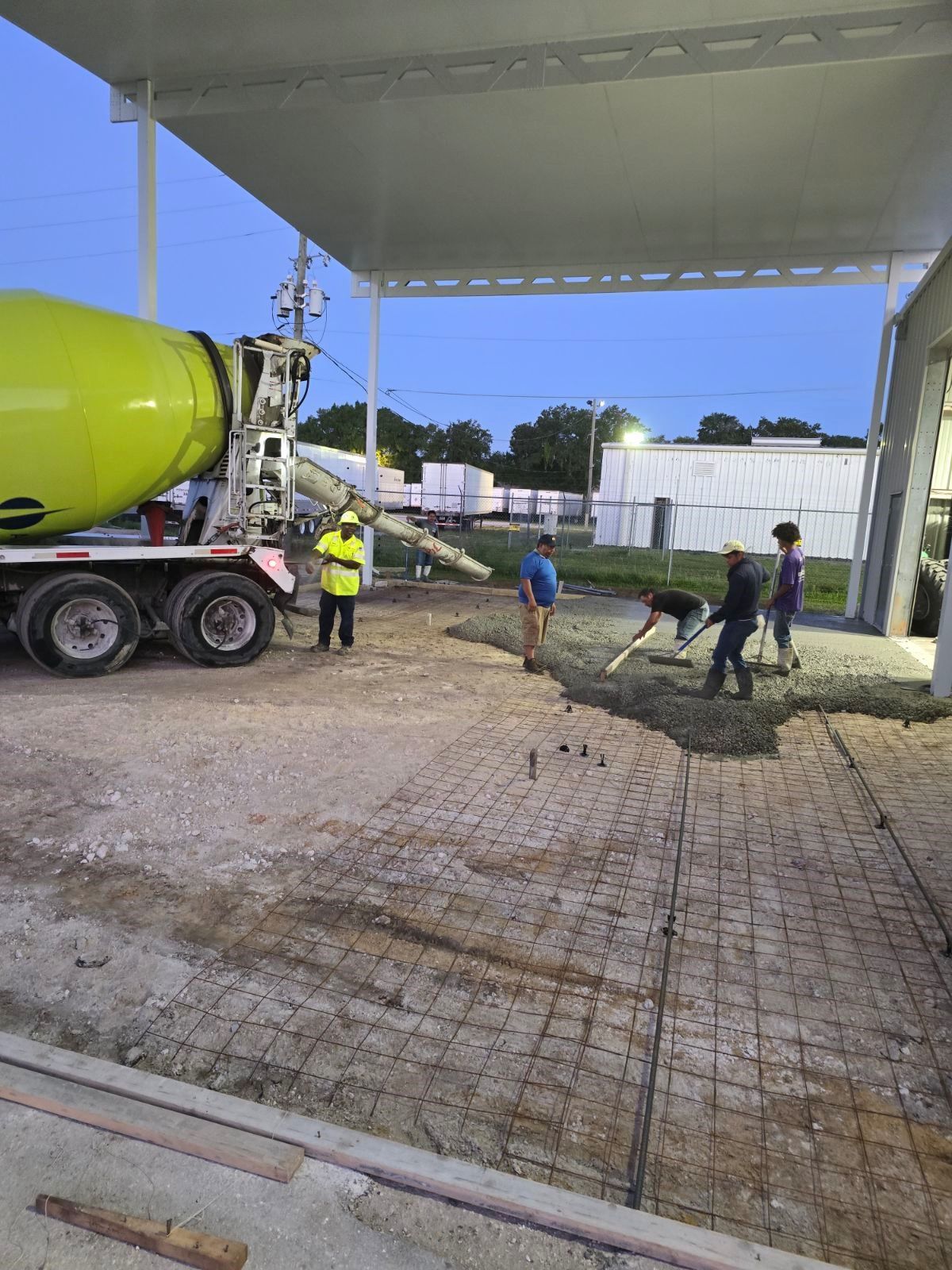 A group of construction workers are pouring concrete into a parking lot.