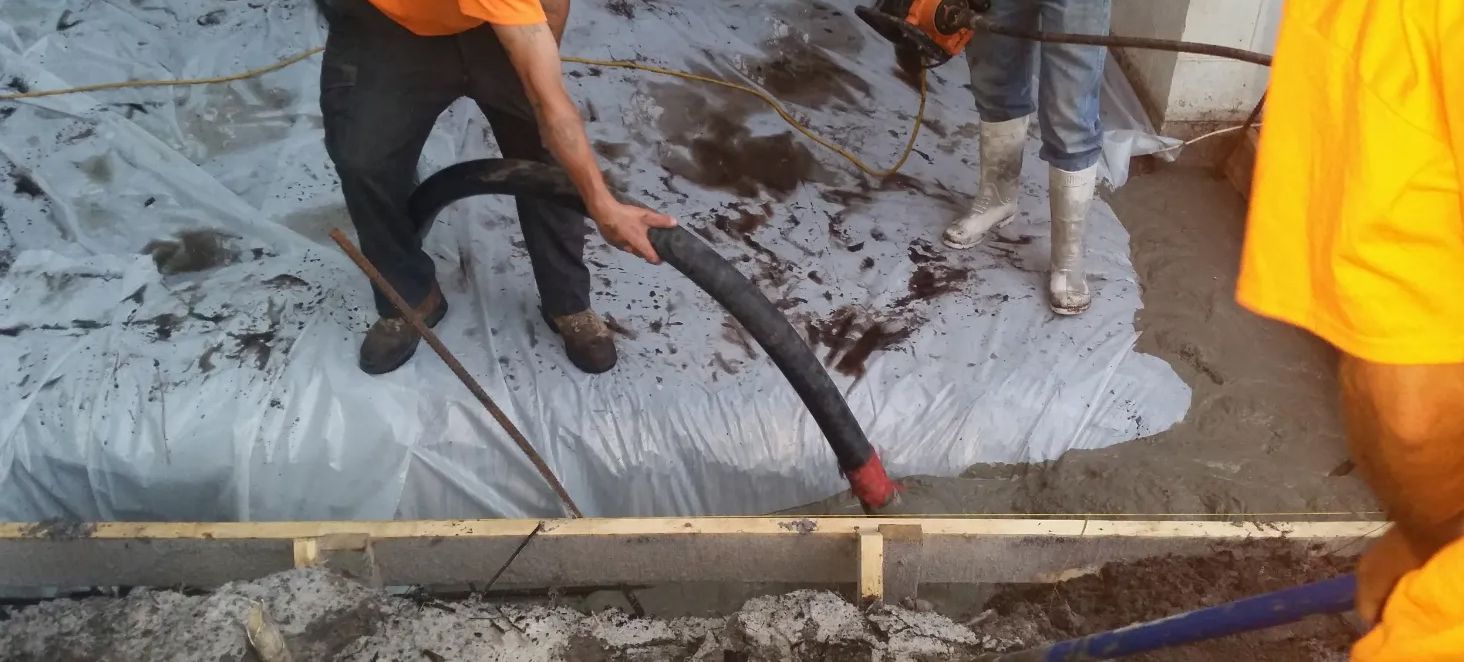 A group of construction workers are working on a concrete floor