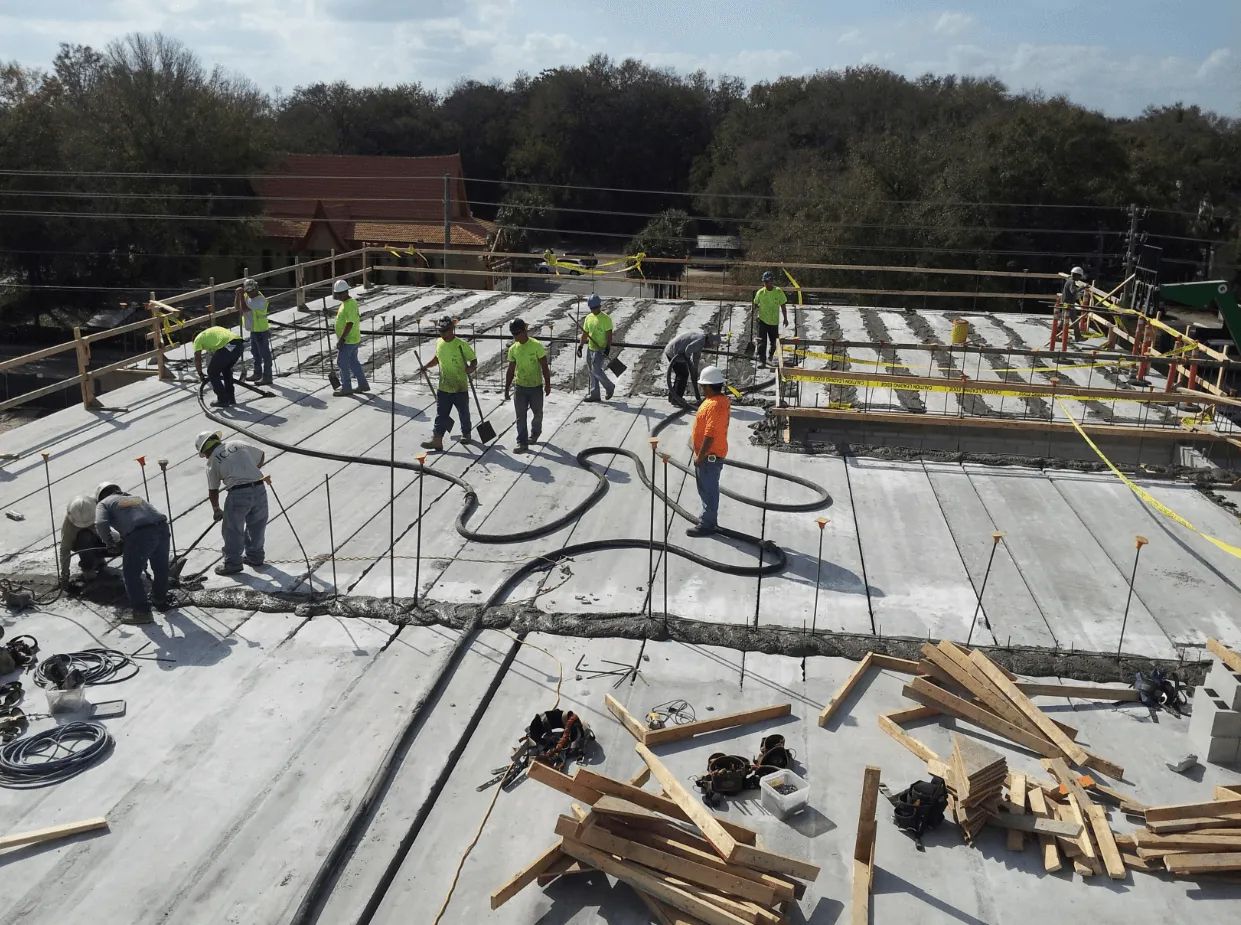 A group of construction workers are working on a concrete floor