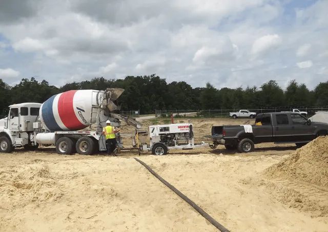 A concrete mixer truck is being towed by a truck