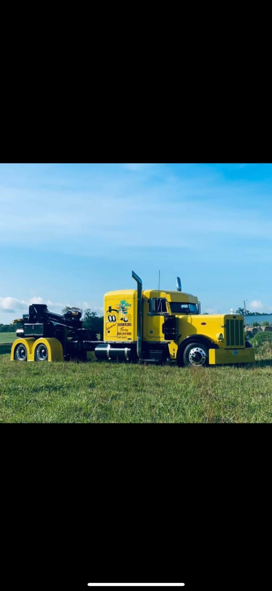 Yellow semi-trucks parked in a field under a clear blue sky