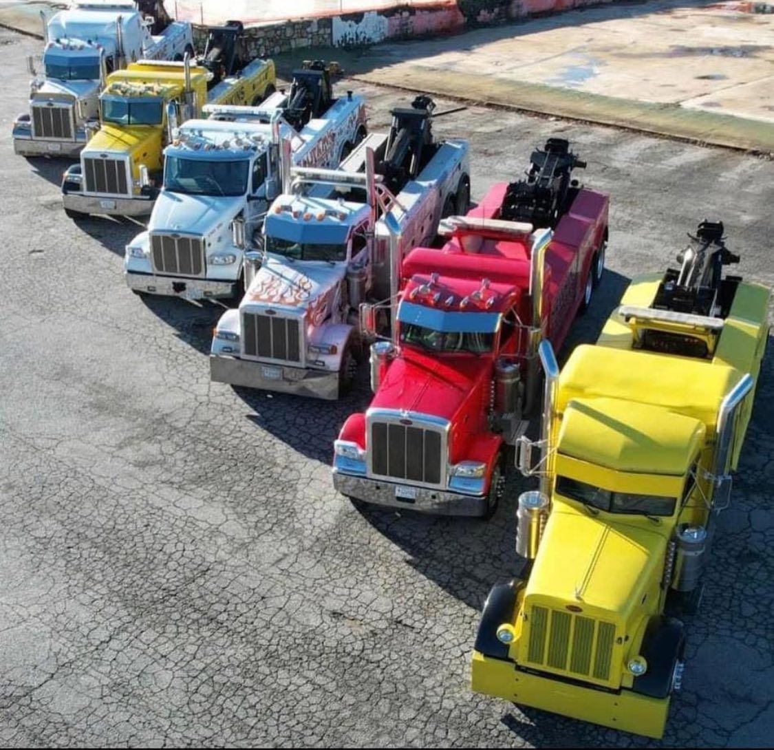 Colorful semi trucks lined up outdoors on cracked pavement, viewed from above.