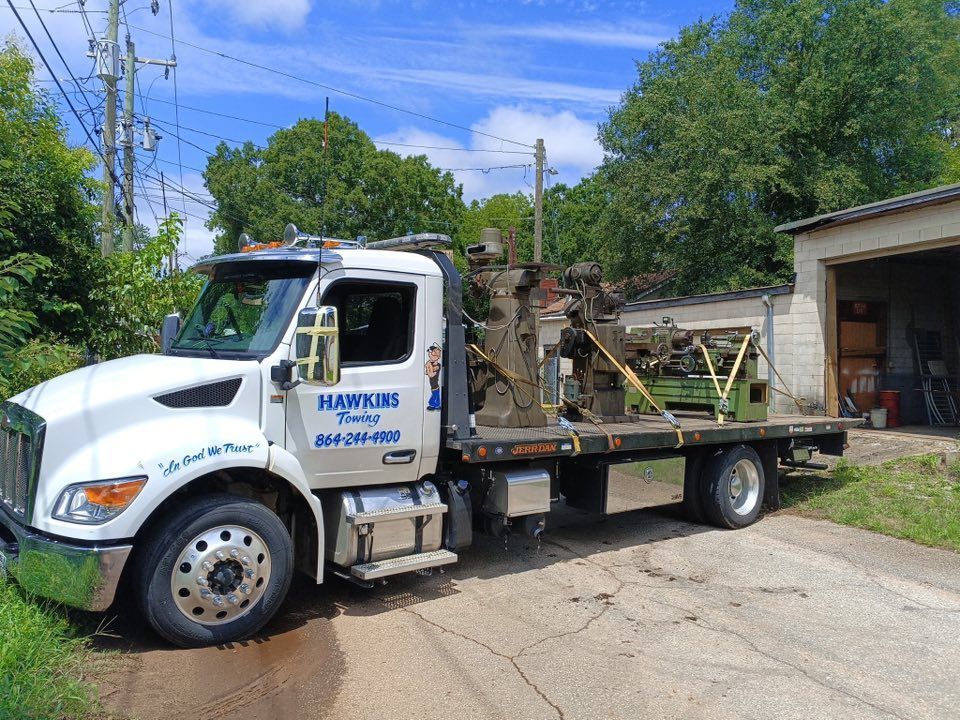 White utility truck with flatbed equipment parked on a driveway beside a garage in a residential area