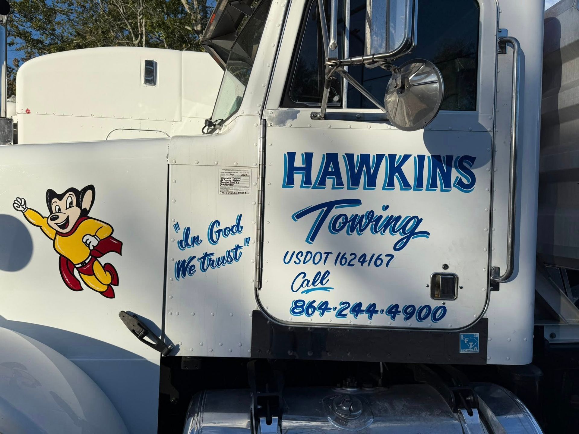 White truck door with “HAWKINS Towing” logo, cartoon tow truck, and phone number.
