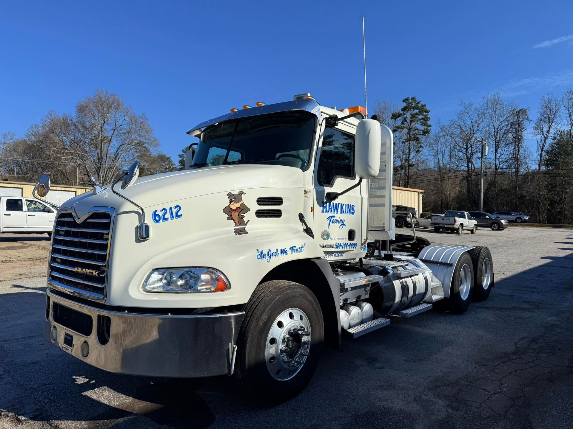 White semi-truck cab parked outdoors on a sunny lot, with chrome front grille and wheels.