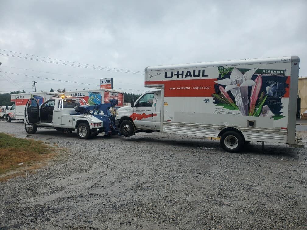 U-Haul truck at roadside crash scene with police and an open vehicle door in overcast weather