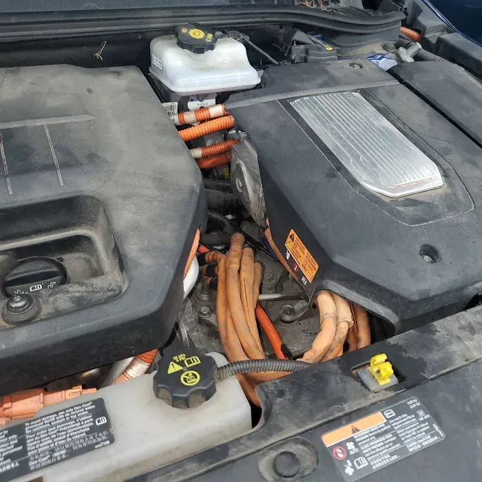 Hybrid engine bay with orange high-voltage cables and black plastic covers.