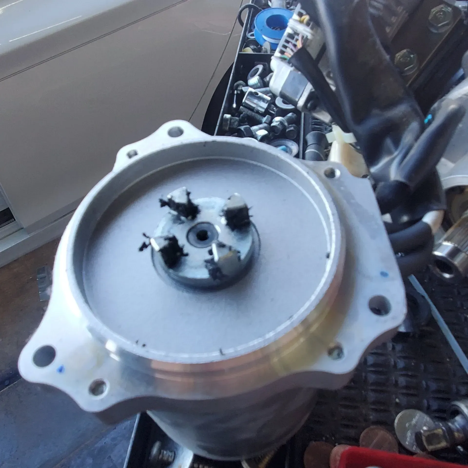 Close-up of a silver metal engine component with a black central shaft in a workshop setting