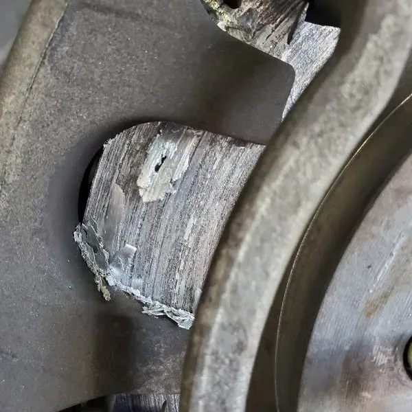 Close-up of a worn brake rotor and caliper with chipped, corroded metal.