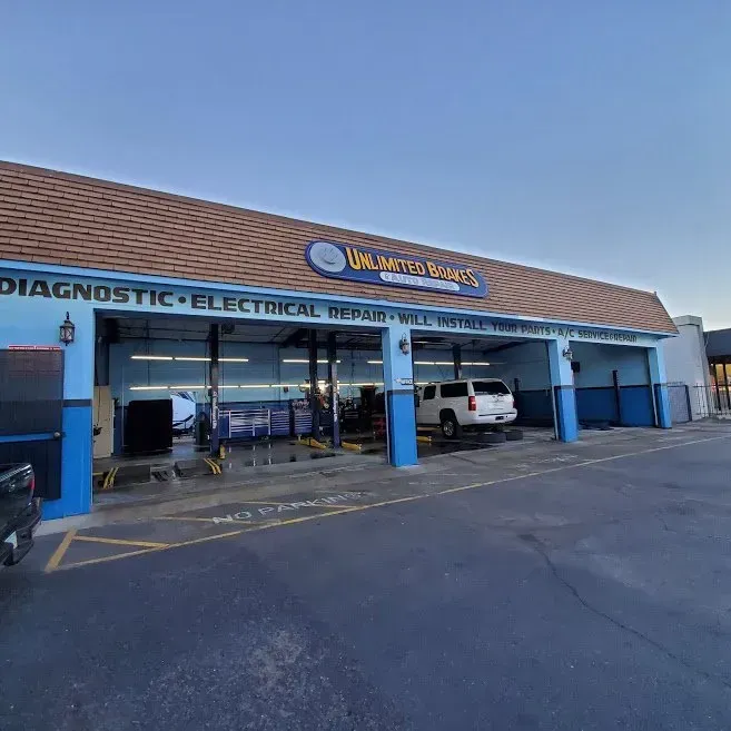 Auto repair shop storefront with blue pillars and parked vehicles under a tiled roof