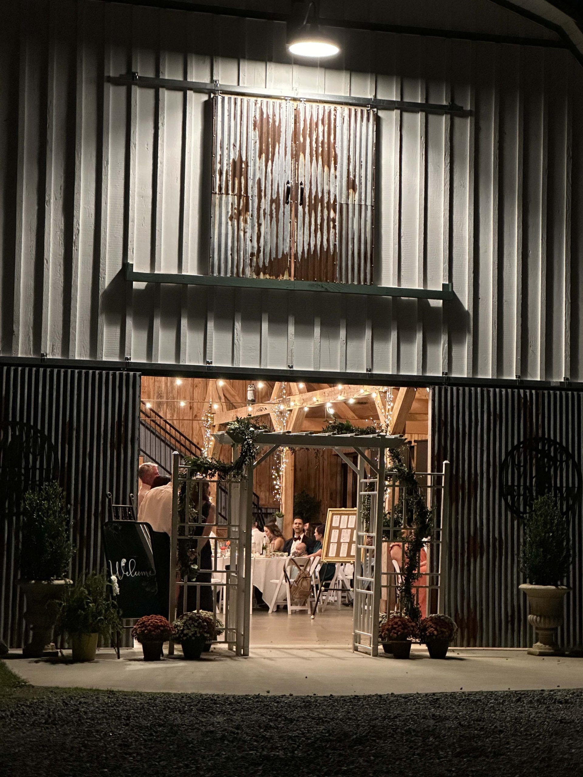 Open storefront with warm lights, metal facade, and outdoor seating at night