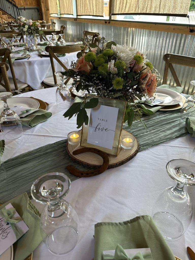Elegant banquet table with white linens, floral centerpiece, candles, and place settings by a window