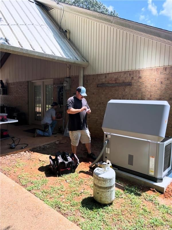 Person standing by a house exterior with a large white appliance and propane tank in the yard
