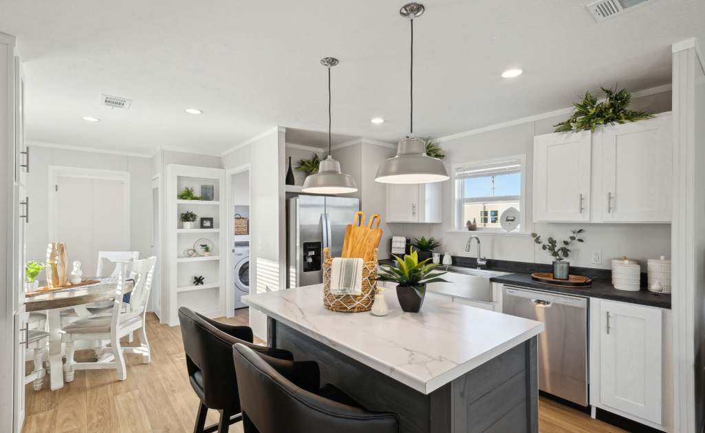Bright modern kitchen with white cabinets, black island, pendant lights, and adjacent dining area