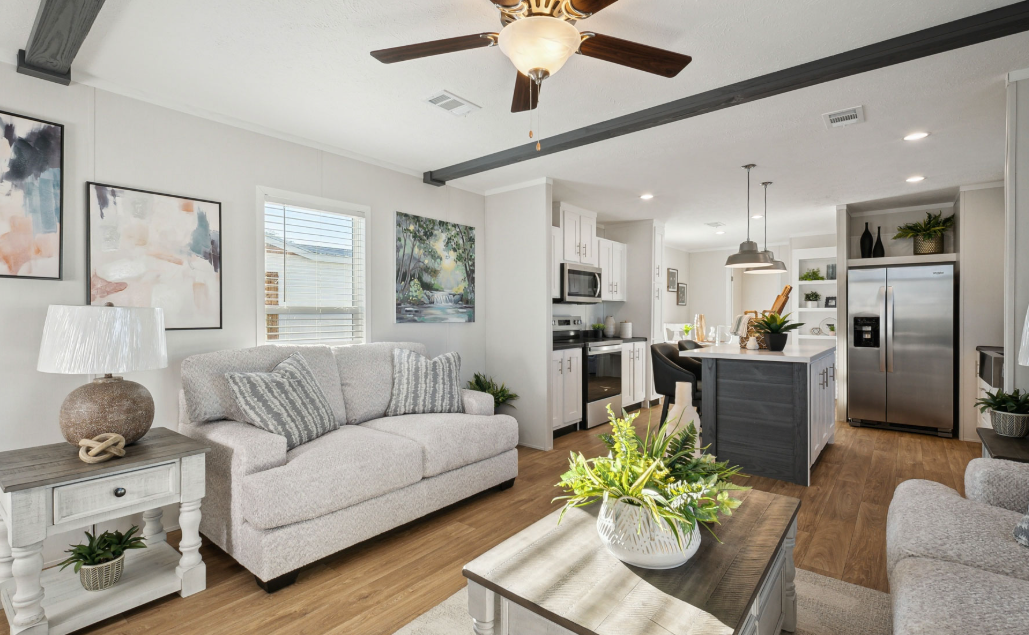 Bright modern living room and kitchen with white sofa, gray island, wood floors, and ceiling fan