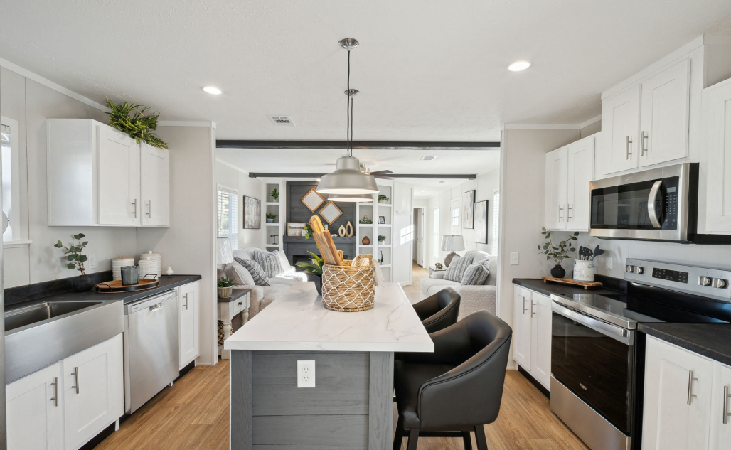 Bright modern kitchen with white cabinets, black countertops, island, and stainless steel appliances