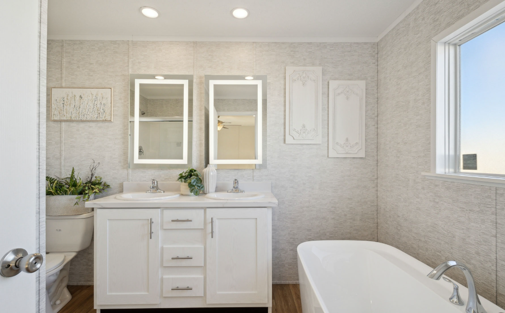 Bright bathroom with white vanity, double mirrors, and a freestanding tub by a large window.