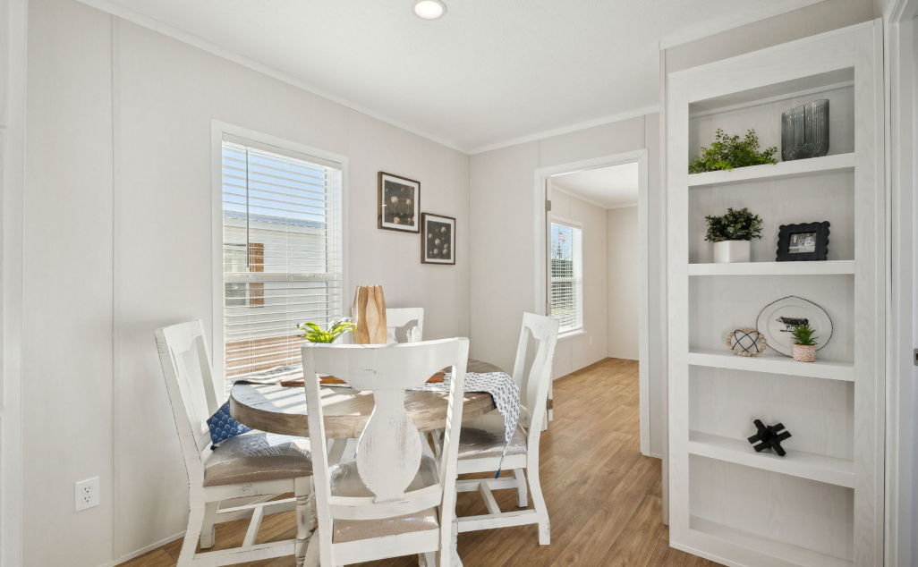 Bright dining room with white table, chairs, shelves, and natural light from a window.