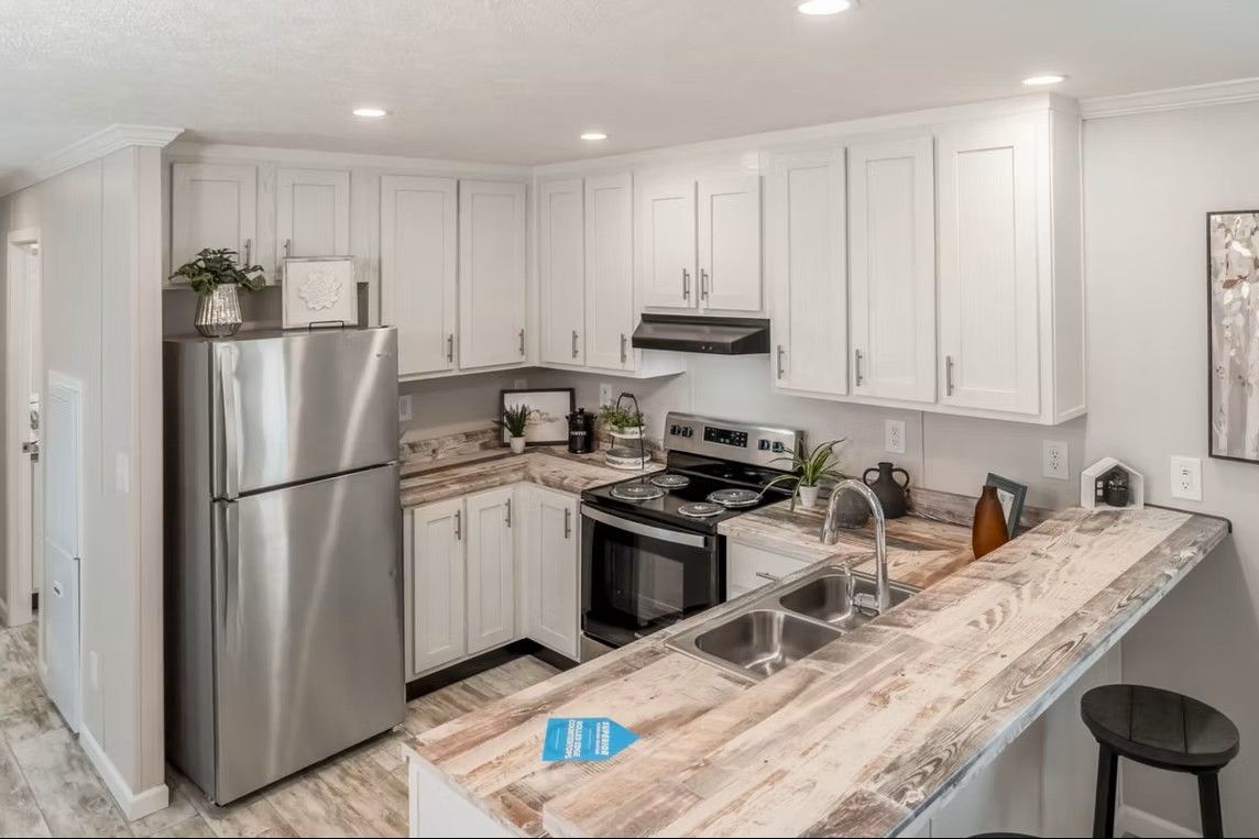 White kitchen with stainless steel appliances, marble countertops, and cabinets.