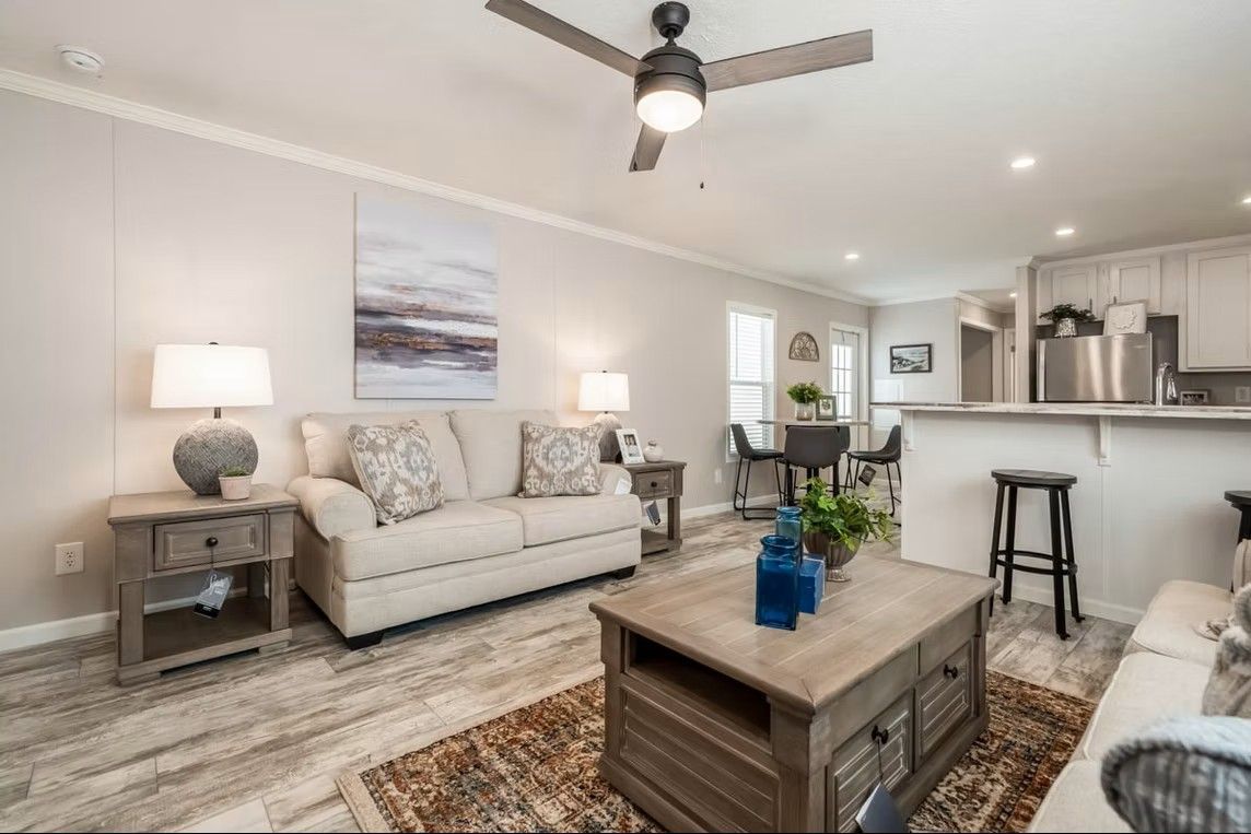 Living room with neutral tones, sofa, coffee table, and open to a dining area.