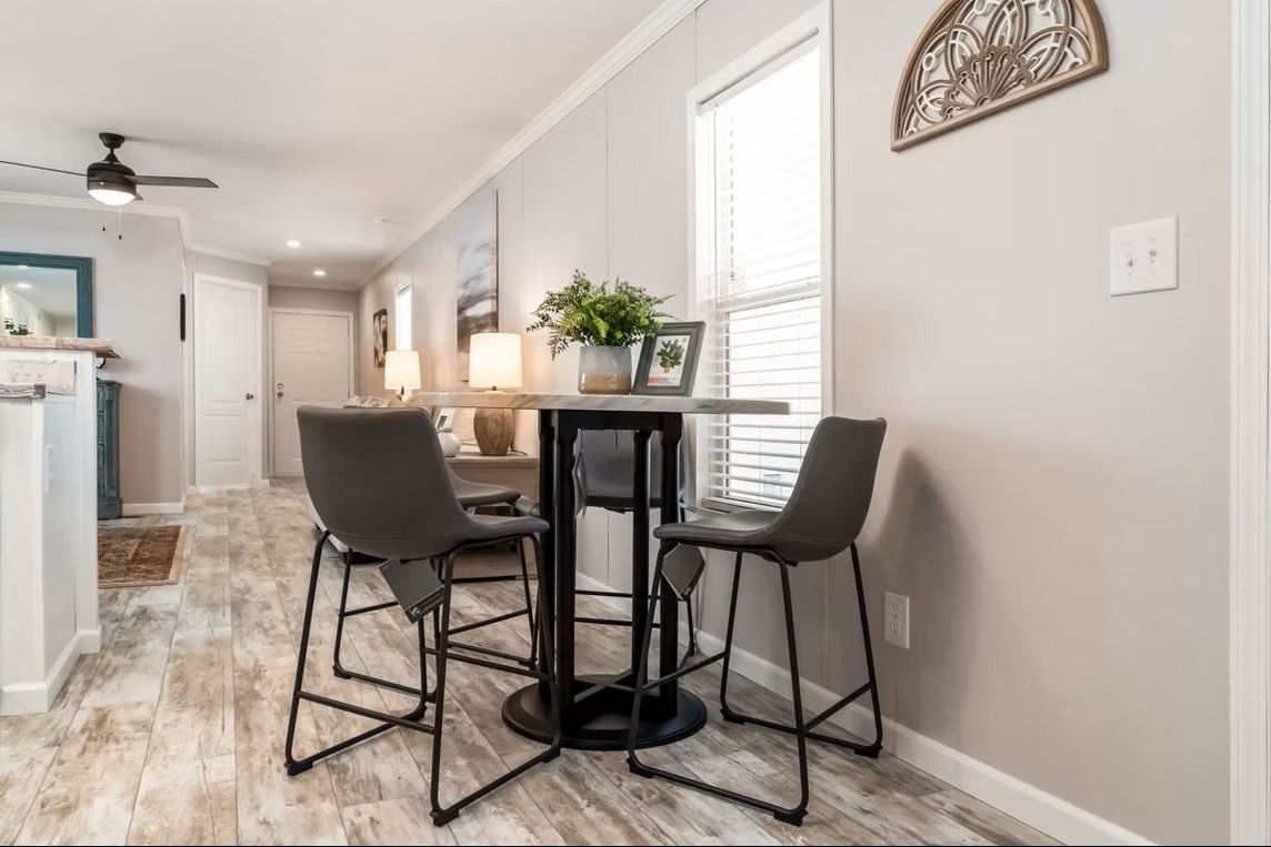 Dining area with a round table, two gray bar stools, and a window.
