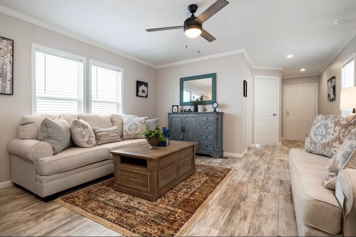 Cozy living room with beige sofa, wooden coffee table, blue cabinet, and ceiling fan.