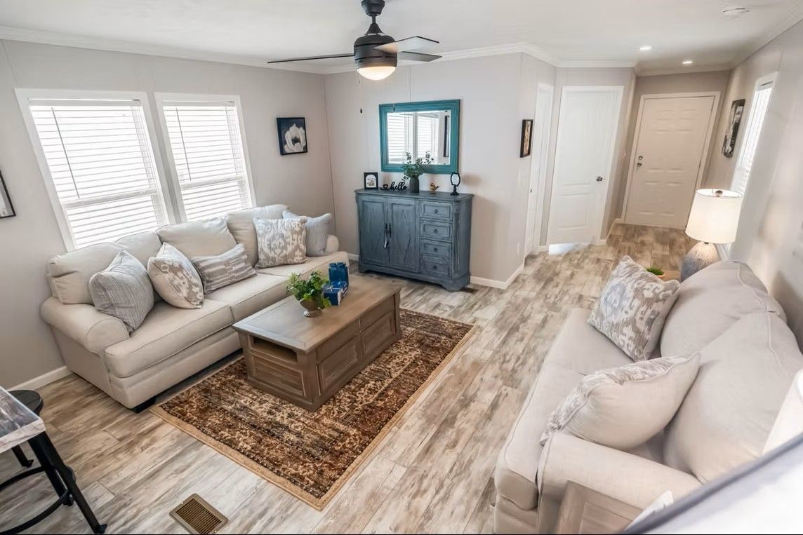 Cozy living room with beige sofas, a wooden coffee table, and a blue cabinet; light wood flooring.