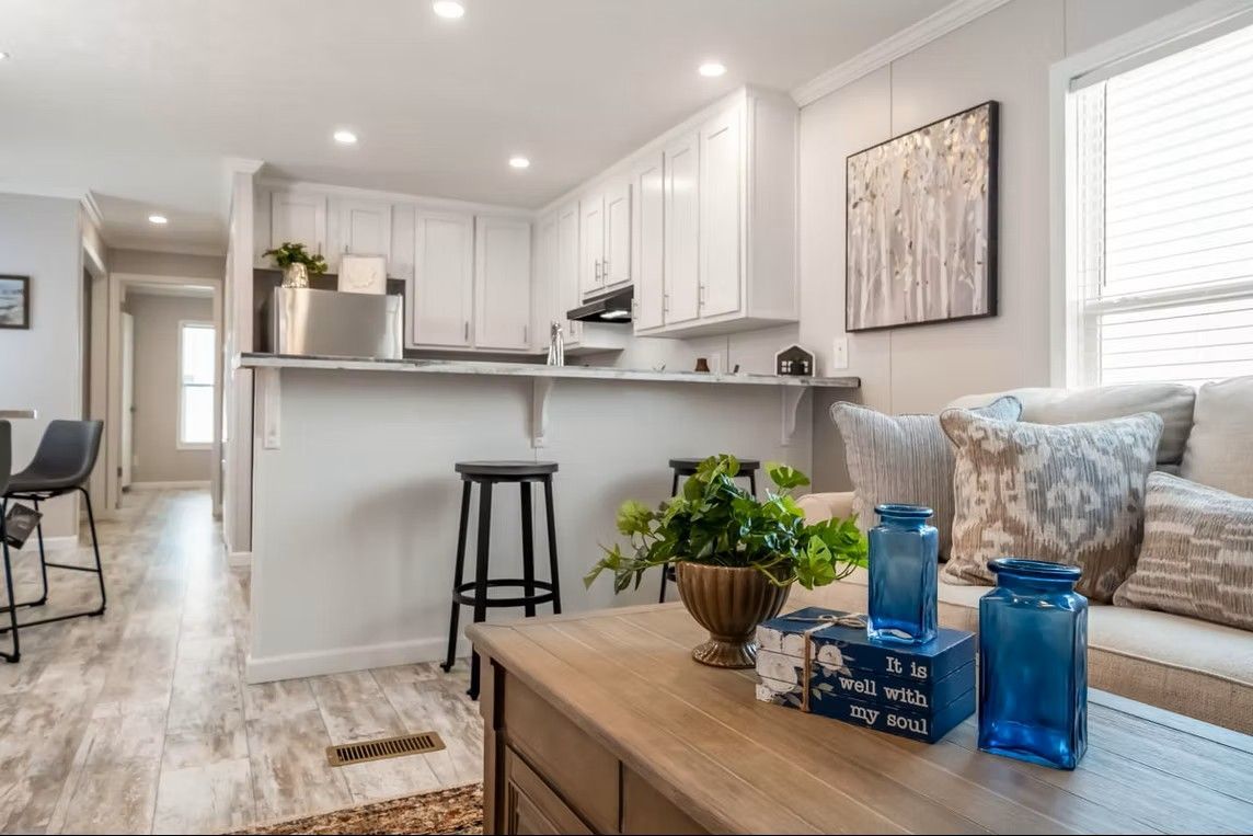 Living room and kitchen with white cabinets, breakfast bar, and window.