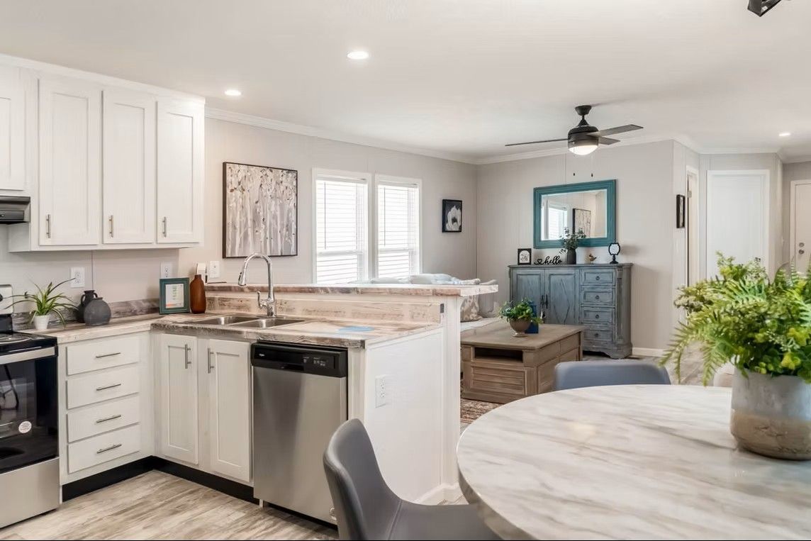 Kitchen and living area of a home with white cabinets, stainless steel appliances, and gray walls.