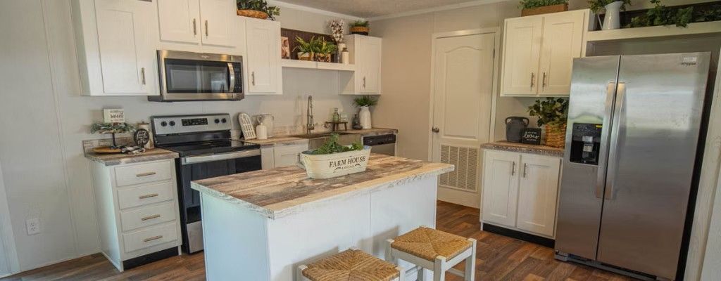 White kitchen with stainless steel appliances, a center island, and wooden floors.