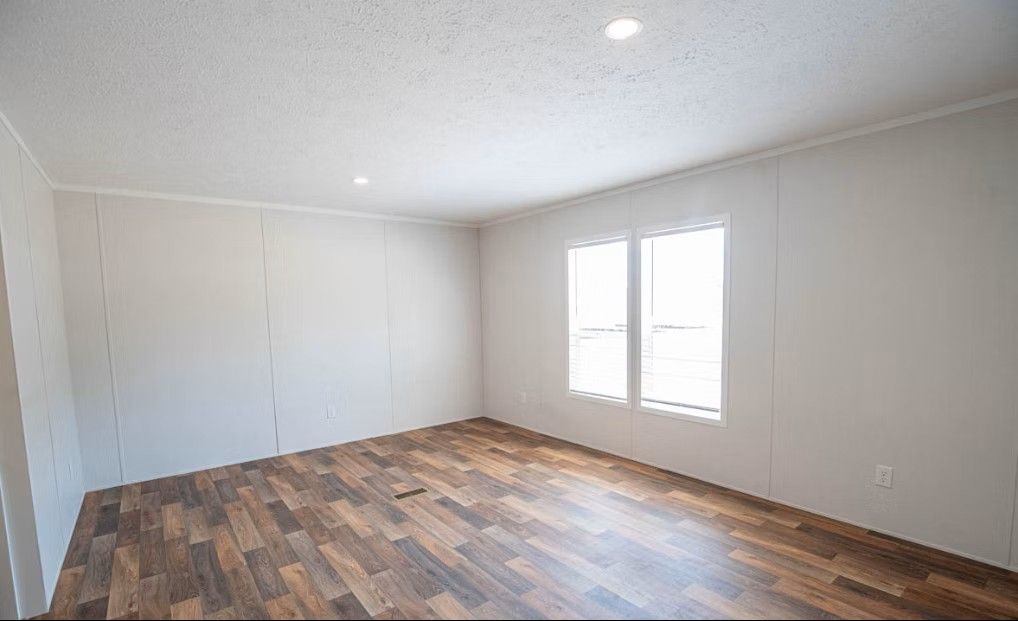 Empty room with wood-look floor, white walls, and a window.
