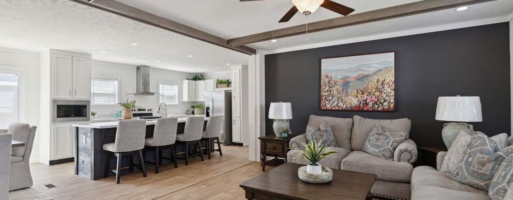 Open-concept living space with a kitchen and living room. A sofa sits in front of a dark gray accent wall.