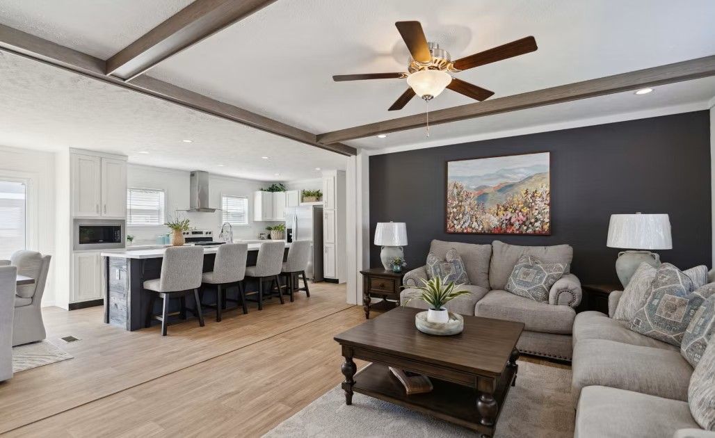Open-concept living space with kitchen, dining area, and seating area. Dark accents, light wood flooring.