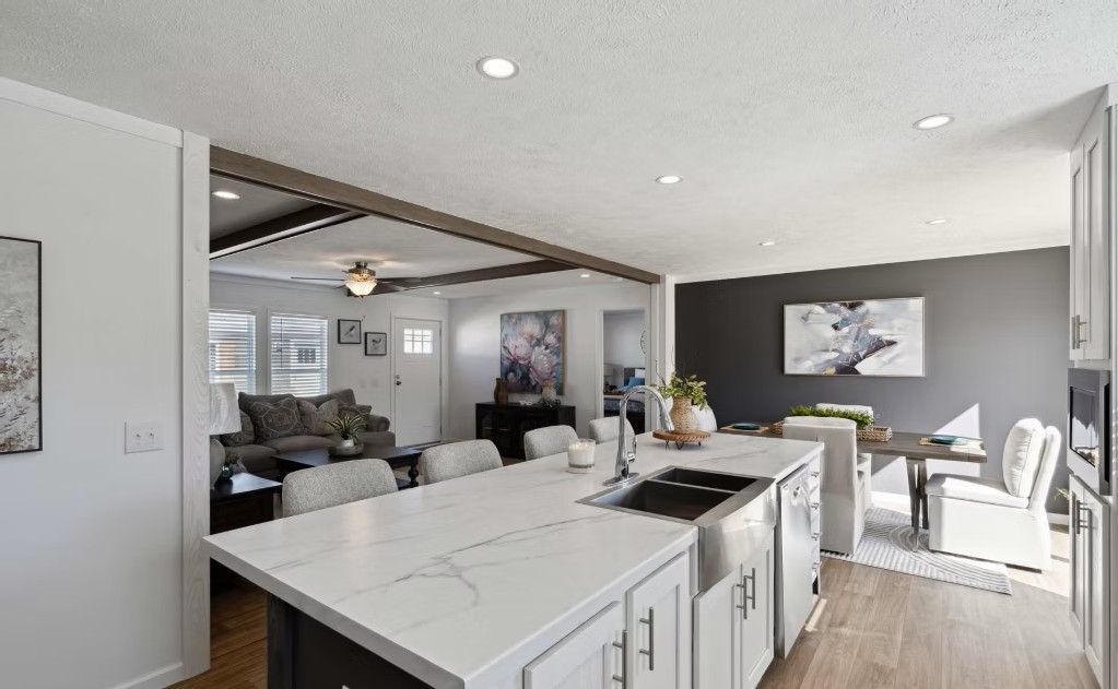 Open-concept kitchen with white island, dark gray cabinets, and adjacent dining area with artwork.