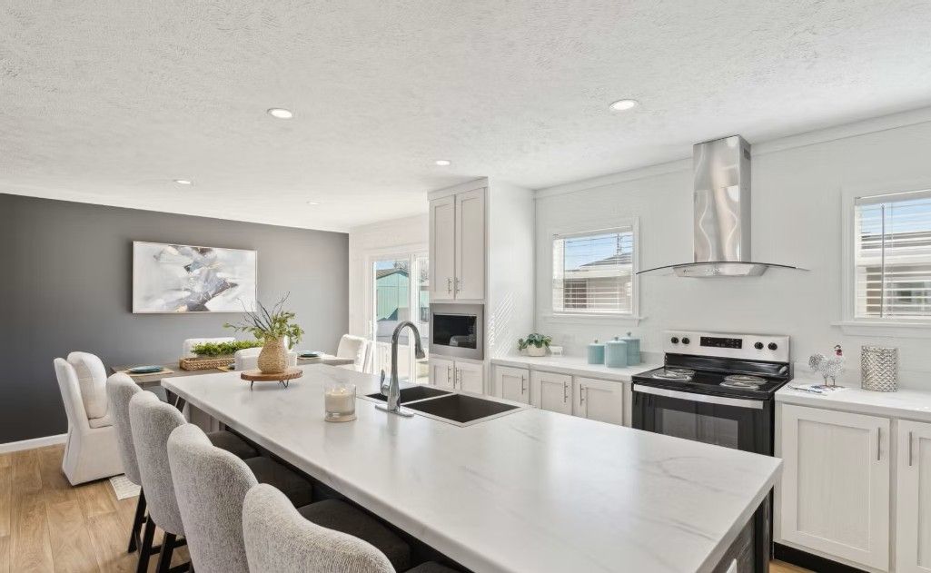 Modern kitchen with a large island, white cabinets, and stainless steel appliances.