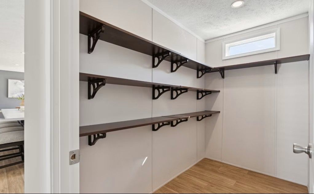Empty pantry with dark shelves, supported by black brackets, against white walls.