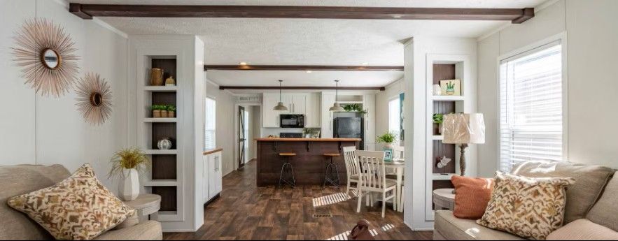 Interior view of a modern home with open layout; living room with sofas, kitchen with island, and dining area.