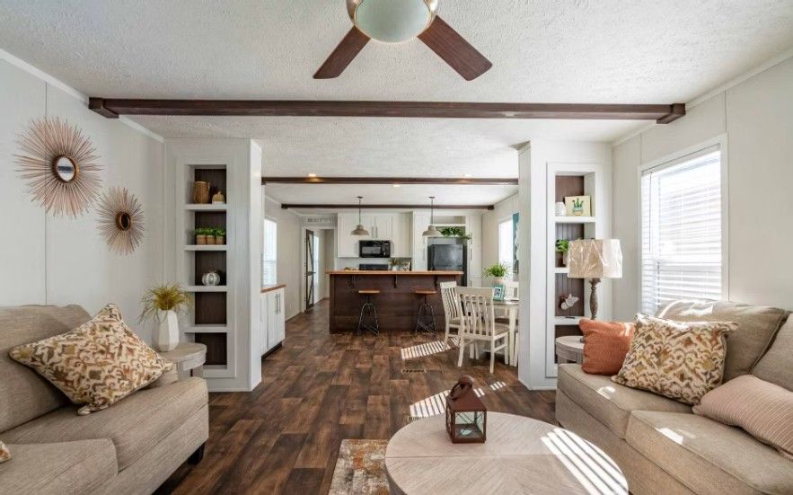 Living room with sofas, built-in shelves, and a view into the kitchen and dining area.