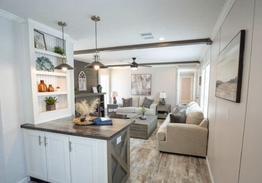 Living room with island, fireplace, and two sofas, light wood floors, and neutral tones.