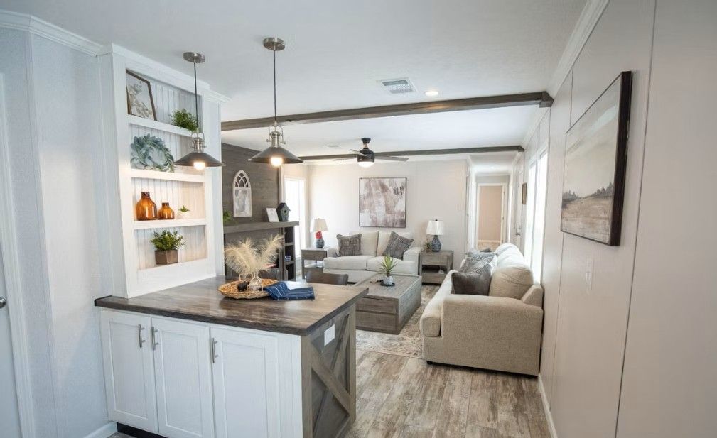 Interior view of a living room and kitchen in a home with neutral tones, a gray island, and wood accents.