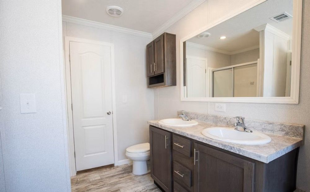 Bathroom with double sink vanity, large mirror, and closed white door.