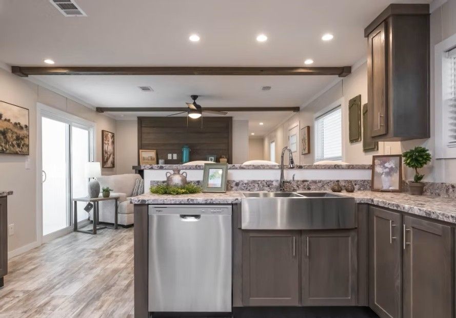 Open kitchen with stainless steel appliances, grey cabinets, and a view into the living room.