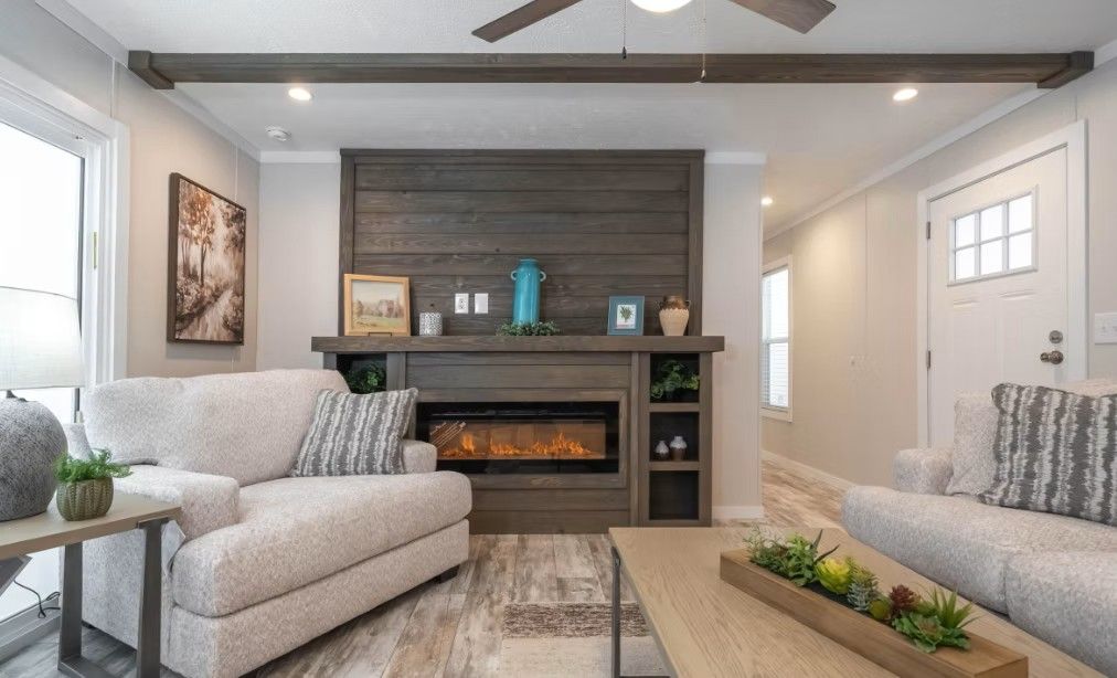 Living room with fireplace, beige sofas, wood beams, and a light wooden floor.