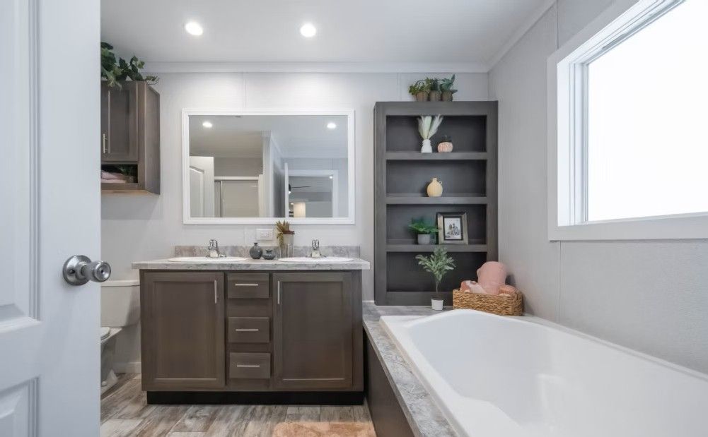 Bathroom with a vanity, soaking tub, bookcase, and large window.