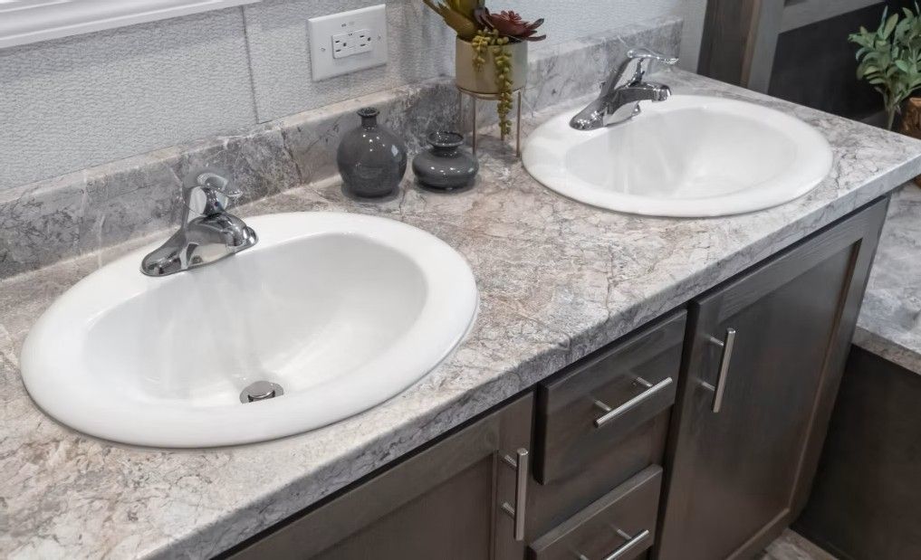 Bathroom vanity with two white sinks, chrome faucets, and a speckled gray countertop.
