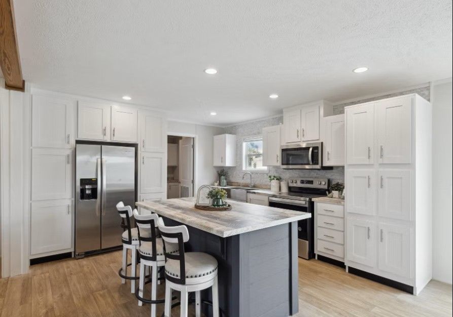 White kitchen with island, stainless steel appliances, and bar stools.