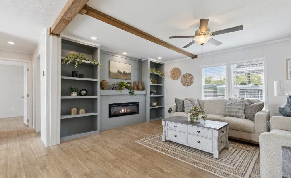 Cozy living room with fireplace, built-in shelves, and beige furniture. Wooden beams, light brown floors.